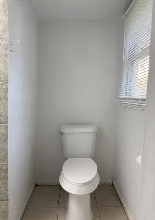 a white toilet sitting in a bathroom next to a window
