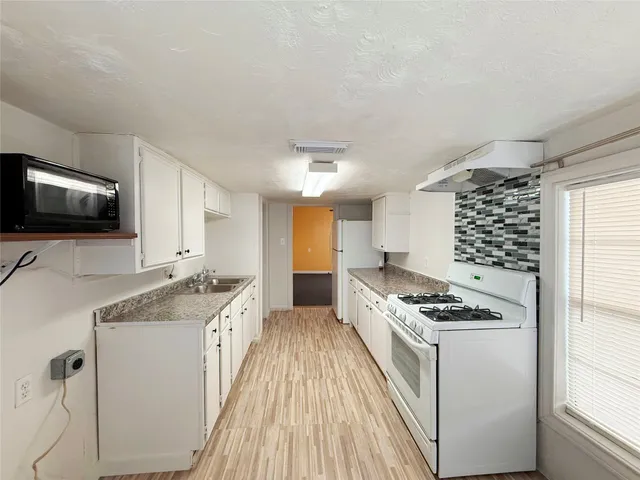 a kitchen with granite countertop a sink stove and cabinets