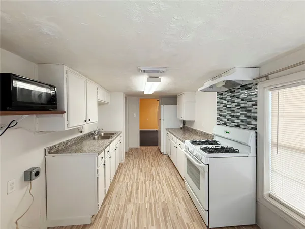 a kitchen with granite countertop a sink stove and cabinets