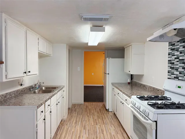 a kitchen with granite countertop a sink stove and cabinets