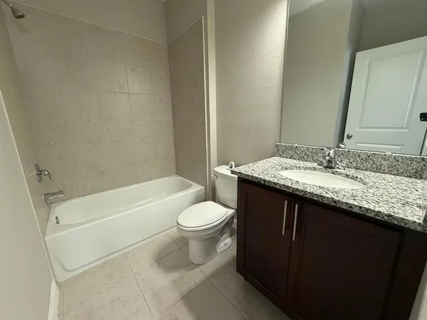 a bathroom with a granite countertop toilet sink and mirror