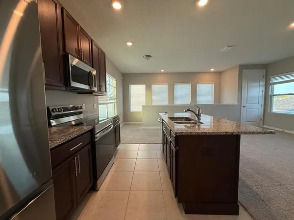 a kitchen with stainless steel appliances granite countertop a sink a stove and a refrigerator