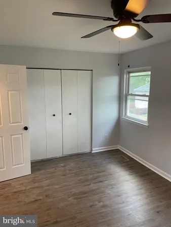 an empty room with wooden floor closet and windows