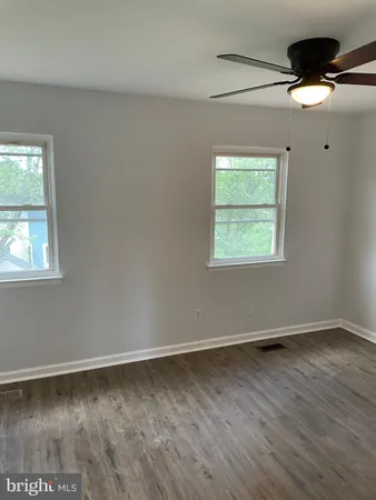 an empty room with wooden floor fan and windows