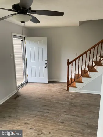 a view of an empty room with wooden floor and stairs