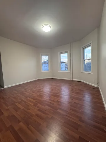 a view of an empty room with wooden floor and window