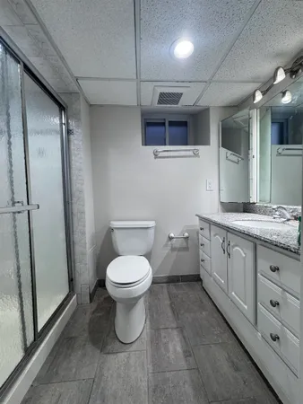a bathroom with a granite countertop toilet a sink a mirror and vanity
