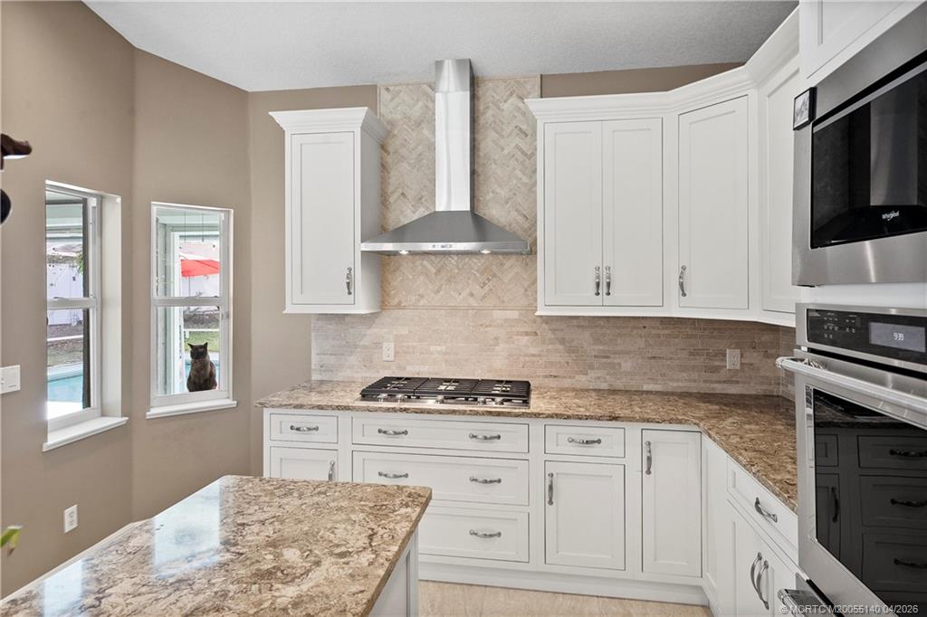 5688 Southeast Pot O Gold Place Stuart, FL 34997 - Photo 15 of 40 a kitchen with granite countertop white cabinets and stainless steel appliances