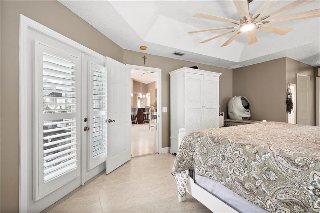 5688 Southeast Pot O Gold Place Stuart, FL 34997 - Photo 20 of 40 a bedroom with a large bed and a chandelier