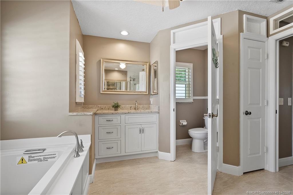 5688 Southeast Pot O Gold Place Stuart, FL 34997 - Photo 23 of 40 a spacious bathroom with a granite countertop sink a toilet and a bathtub