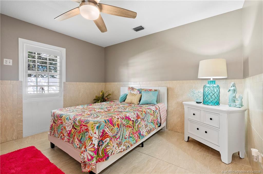 5688 Southeast Pot O Gold Place Stuart, FL 34997 - Photo 24 of 40 a bedroom with a bed and a lamp on dresser