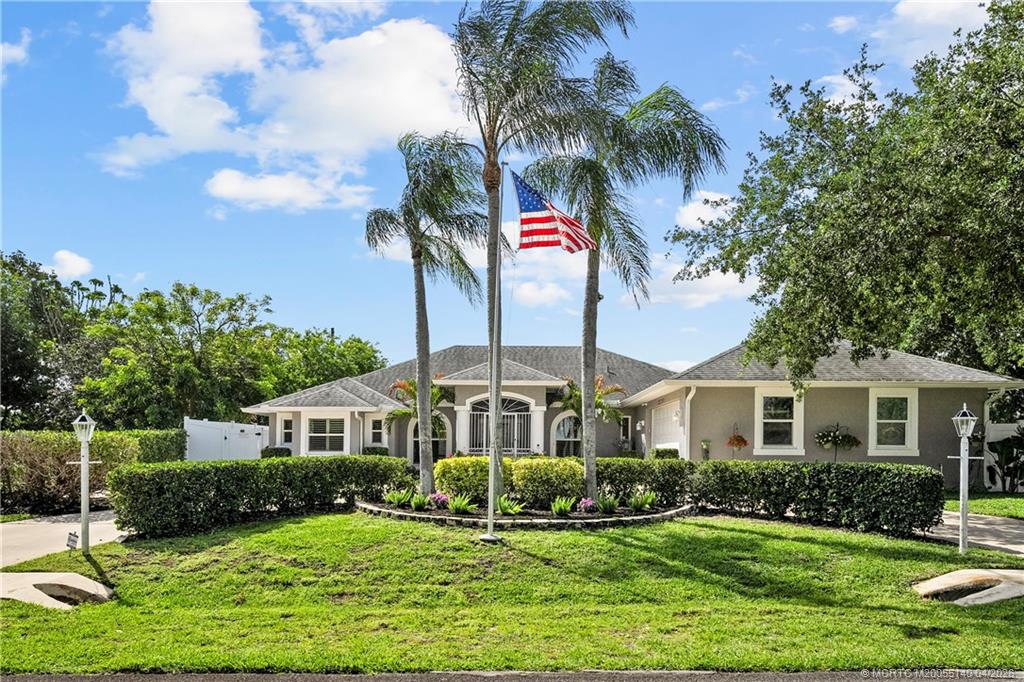 5688 Southeast Pot O Gold Place Stuart, FL 34997 - Photo 3 of 40 a front view of a house with yard and green space