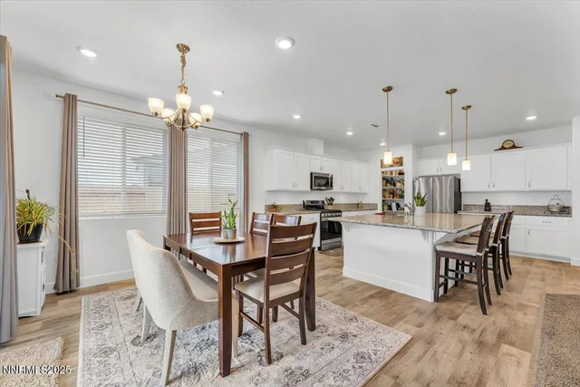 a kitchen with stainless steel appliances kitchen island granite countertop a table chairs stove and white cabinets