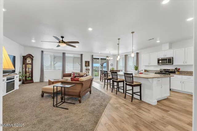 a dining room with stainless steel appliances kitchen island granite countertop a dining table chairs and a refrigerator