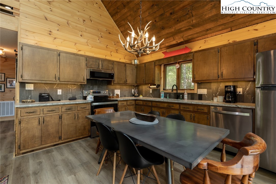 495 Horseshoe Ridge Road East Deep Gap, NC 28618 - Photo 12 of 33 a kitchen with a dining table chairs stainless steel appliances and cabinets