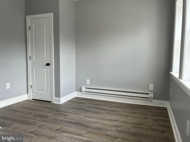 an empty room with wooden floor and window