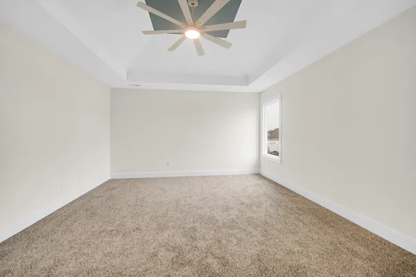 an empty room with windows and ceiling fan