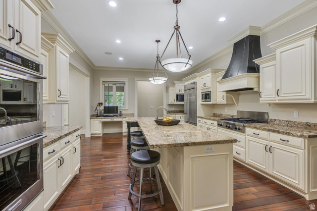 650 East Center Street Alpine, UT 84004 - Photo 8 of 38 Spacious kitchen featuring an expansive center island with seating, cream-colored cabinetry, stainless steel appliances, granite countertops, and rich wood-finish flooring