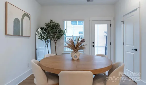 a dining room with wooden floor furniture and kitchen view