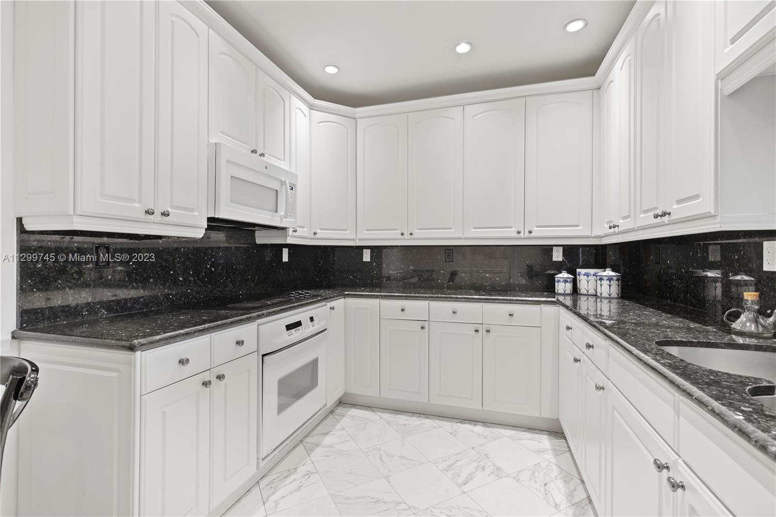 151 Crandon Boulevard, Unit 340 Key Biscayne, FL 33149 - Photo 8 of 26 a white kitchen with granite countertop stainless steel appliances