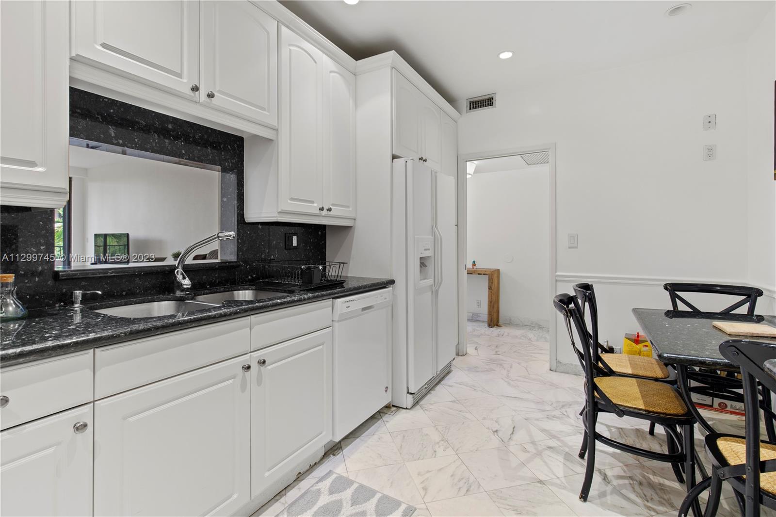 151 Crandon Boulevard, Unit 340 Key Biscayne, FL 33149 - Photo 9 of 26 a kitchen with granite countertop a sink white cabinets and white appliances