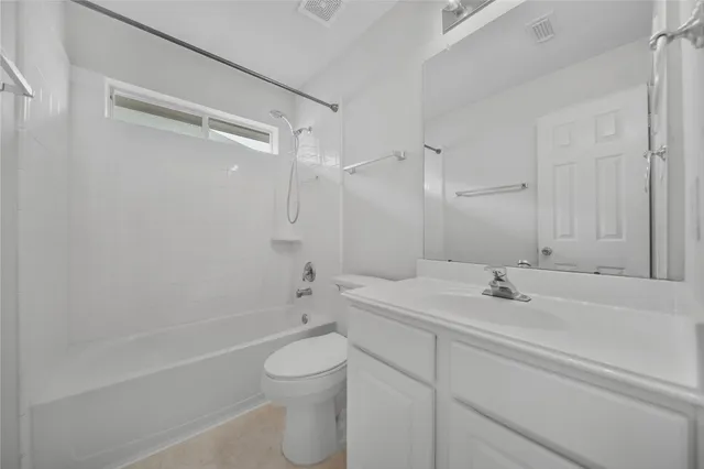 an empty room with a chandelier fan and windows