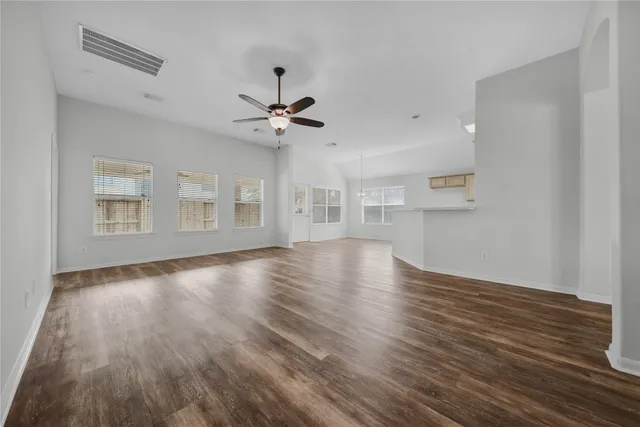 a view of an empty room with window and wooden floor