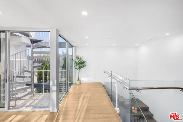a view of a hallway with wooden floor and windows