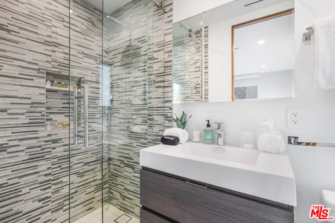 6410 Lindenhurst Avenue Los Angeles, CA 90048 - Photo 28 of 39 a bathroom with a sink a mirror and shower