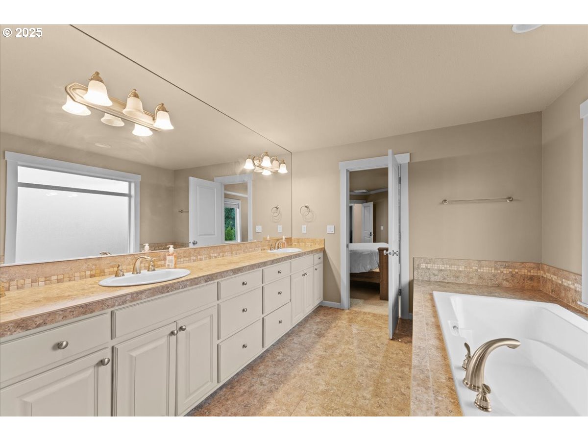 15485 Southwest Willamette Valley Court Beaverton, OR 97007 - Photo 26 of 48 a spacious bathroom with a granite countertop double vanity sink a mirror and a bathtub