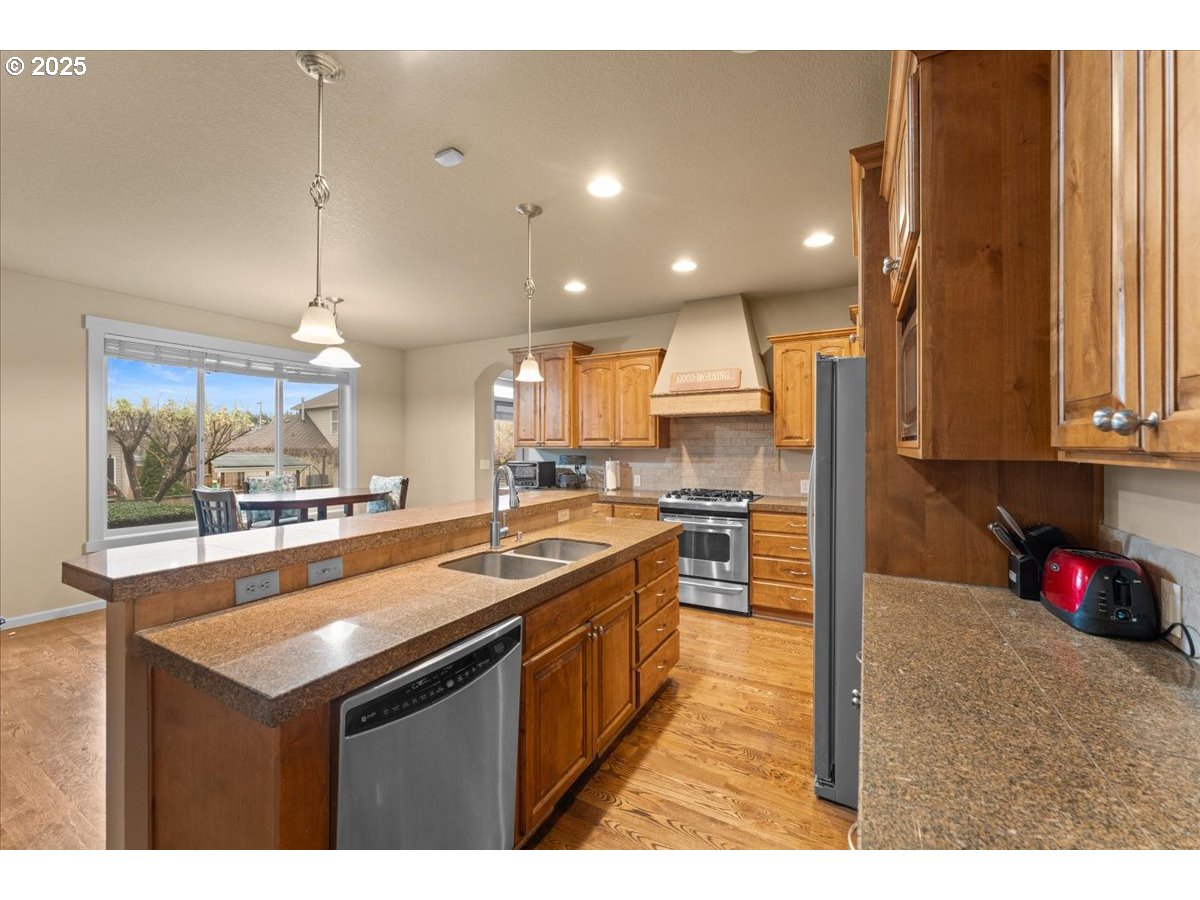 15485 Southwest Willamette Valley Court Beaverton, OR 97007 - Photo 7 of 48 a kitchen with kitchen island granite countertop a sink counter top space and stainless steel appliances