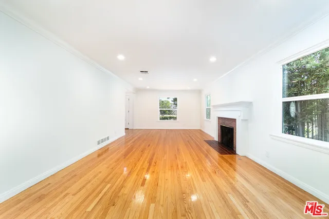 a view of empty room with wooden floor and fireplace