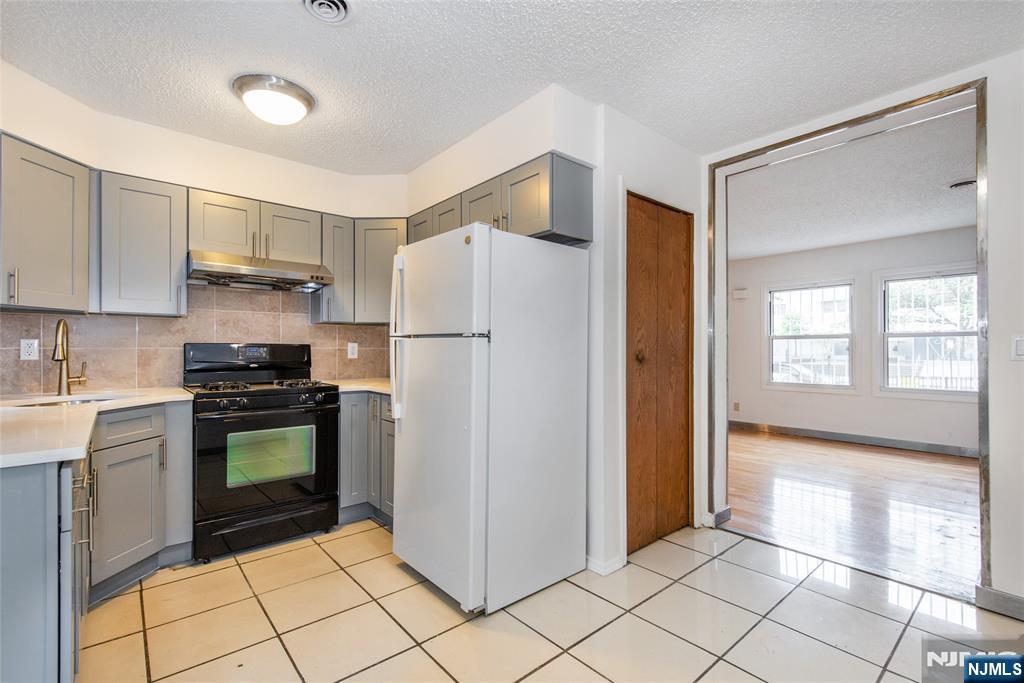 553 Ocean Avenue Jersey City, NJ 07305 - Photo 7 of 27 a kitchen with a refrigerator a stove top oven and cabinets