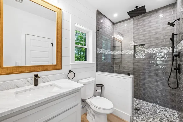 a bathroom with a sink toilet a mirror and shower