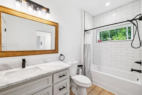 a bathroom with a granite countertop sink a toilet and bathtub