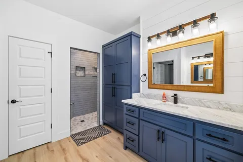 a spacious bathroom with a granite countertop sink a mirror and a shower
