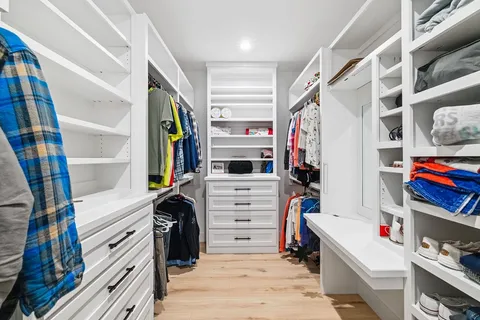 a view of walk in closet with clothes and shoes