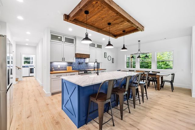 a kitchen with stainless steel appliances a table chairs refrigerator and cabinets