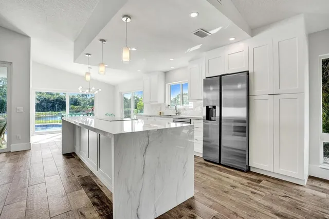 a kitchen with stainless steel appliances a refrigerator and a wooden floor
