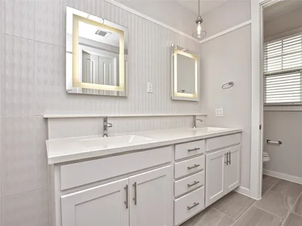 a bathroom with a double vanity sink a mirror and a bathtub
