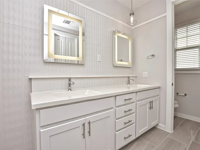 a bathroom with a double vanity sink a mirror and a bathtub
