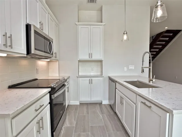 a kitchen with granite countertop a sink stainless steel appliances and cabinets