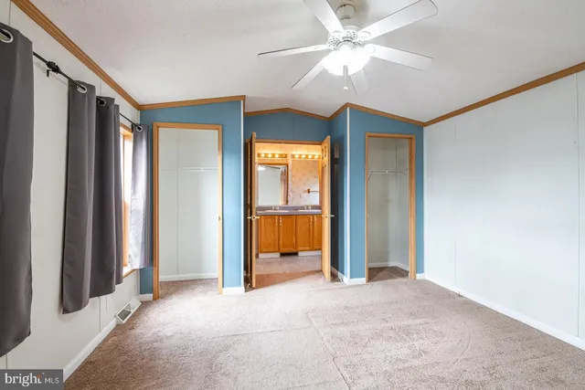 an empty room with closet and a chandelier fan
