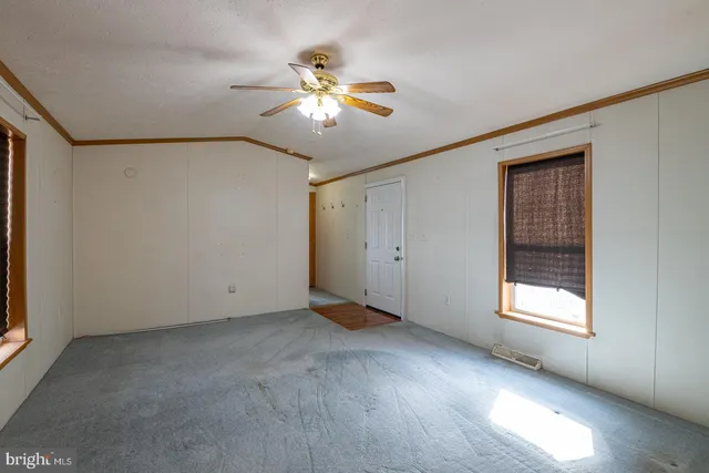 an empty room with windows and fan