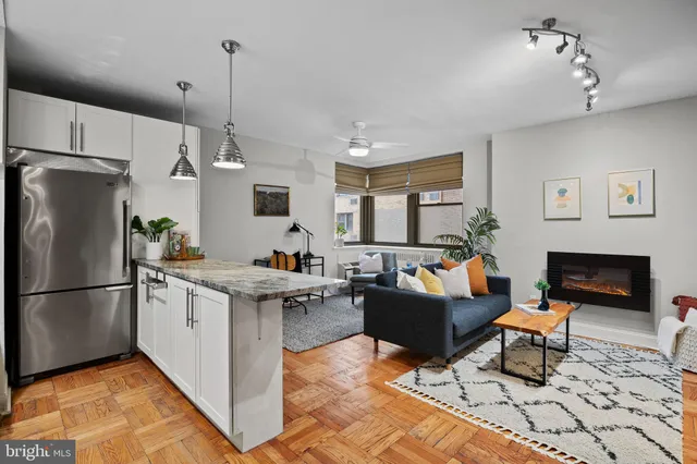 a kitchen with stainless steel appliances granite countertop a stove refrigerator and couches with wooden floor