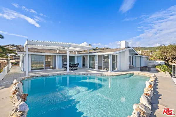 a view of a house with pool fire pit a table and chairs in patio