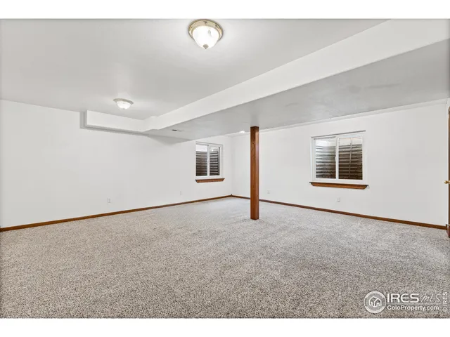 a view of an empty room with wooden floor and windows