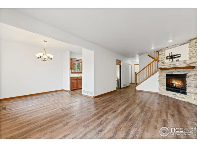 a view of an empty room with wooden floor fireplace and a window