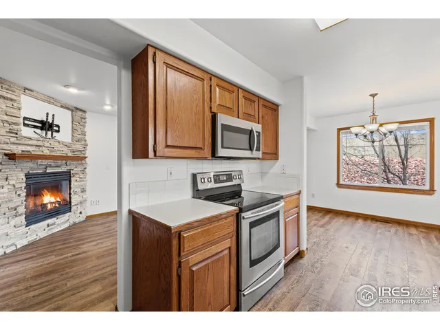 a kitchen with stainless steel appliances granite countertop a stove top oven a sink dishwasher and a fireplace with wooden floor