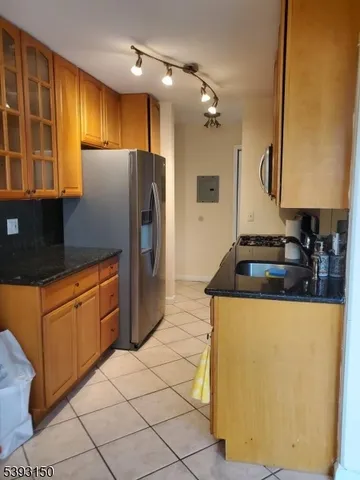 a kitchen with stainless steel appliances granite countertop a refrigerator a sink dishwasher and wooden cabinets